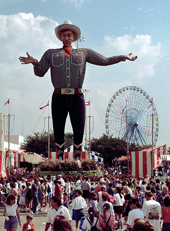 Big Tex stands tall as the crowd mills about at the Texas State Fair.